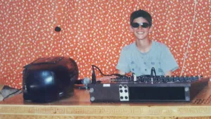 Photographie de DJ Mazout lorsqu'il était petit, derrière les platines, souriant.