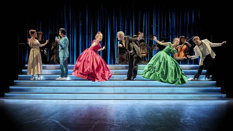 Six comédiens sur scène, costumés à l'occasion d'un bal dansant, musiciens en arrière plan