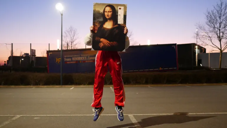 Une personne porte un jogging rouge et saute, portant La Joconde devant son visage