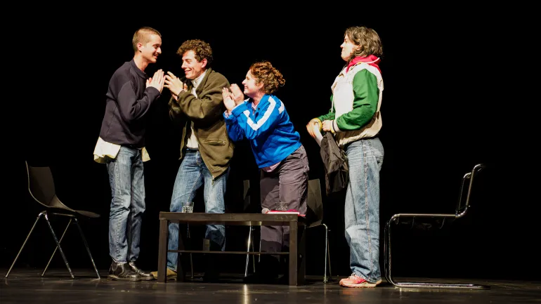 Deux femmes et deux hommes debout sur la scène, grands sourires au visage, l'air heureux, tapant dans leurs mains.