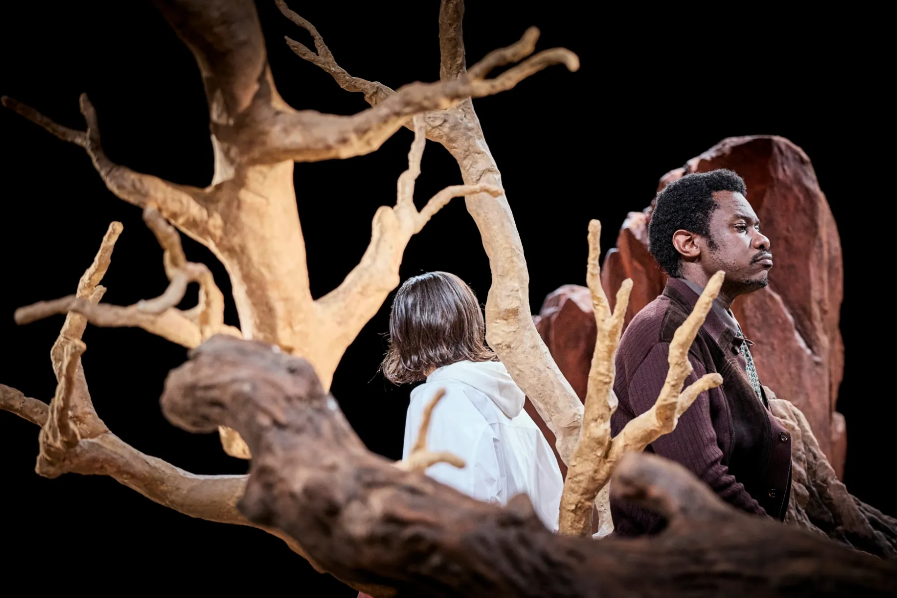 Le père et sa fille assis dos-à-do sur un arbre couché, les branches occupent beaucoup l'image