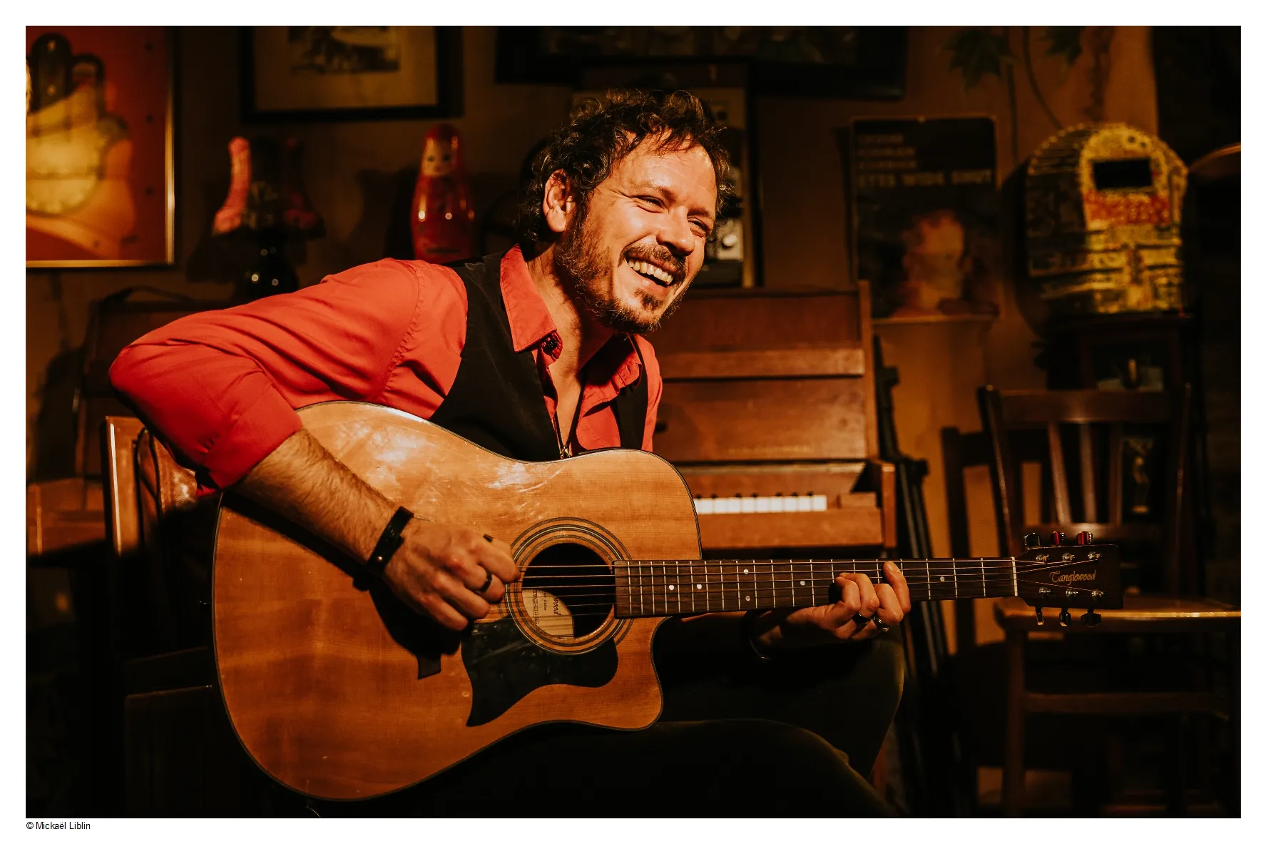 Portrait du musicien Gil, souriant et jouant de la guitare.