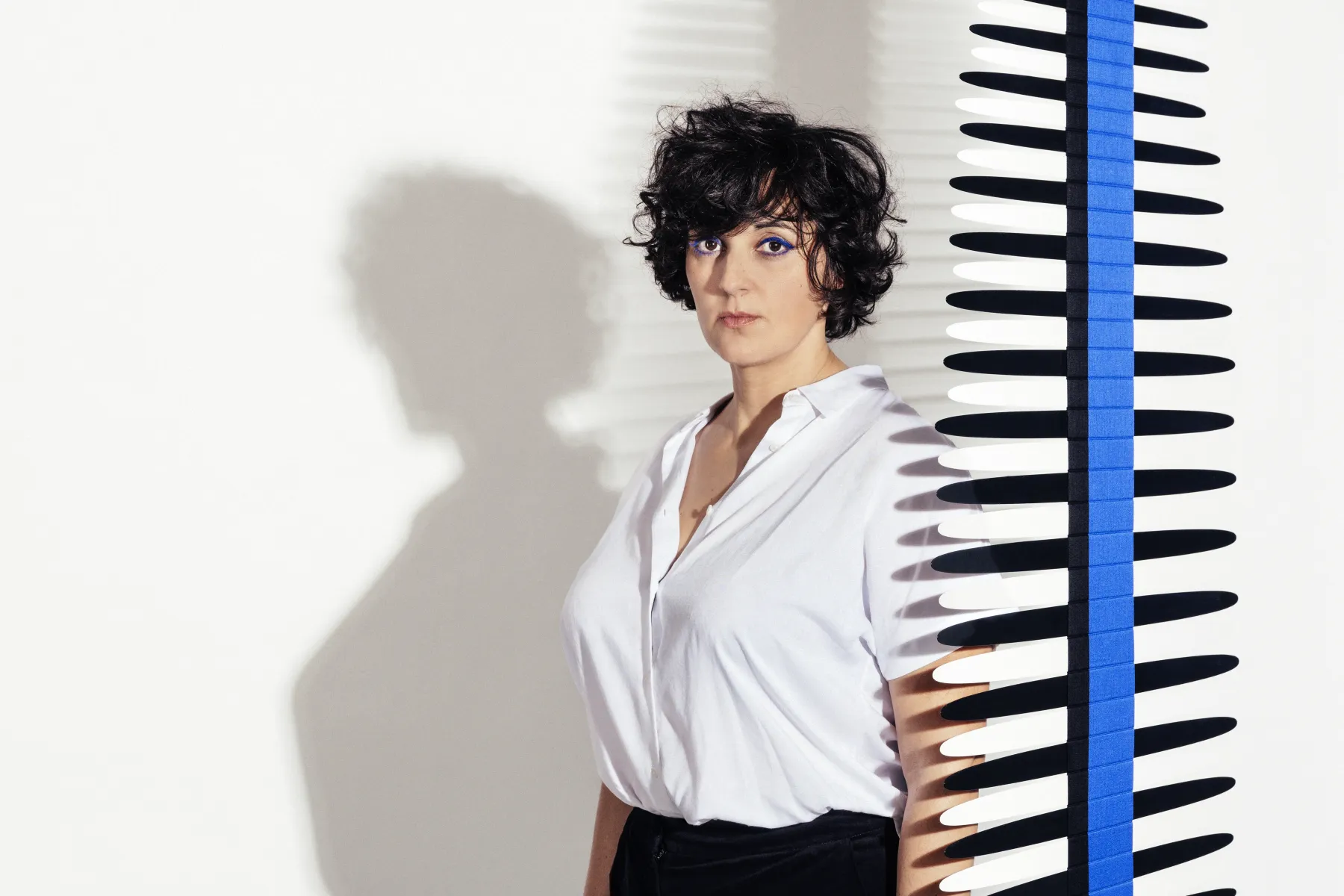 Portrait de Marion Rampal sur fond blanc, portant un chemisier blanc et regardant la caméra